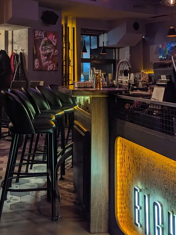 The bar: black leather stools, Edison lamps and the backlit Eight18n panel